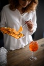 Young attractive woman holds metal tray with slices of orange and takes one piece with tweezers Royalty Free Stock Photo