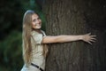 Young attractive woman hugging a big tree in park and smiling Royalty Free Stock Photo