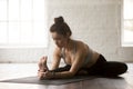 Young attractive woman in Janu Sirsasana pose, white loft studio Royalty Free Stock Photo