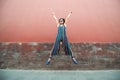 Young attractive woman jumping outdoor over red wall, image toned. Chinese girl amuses, summertime. Beautiful asian model has fun Royalty Free Stock Photo