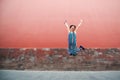 Young attractive woman jumping outdoor over red wall, image toned. Chinese girl amuses, summertime. Beautiful asian model has fun Royalty Free Stock Photo