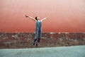 Young attractive woman jumping outdoor over red wall, image toned. Chinese girl amuses, summertime. Beautiful asian model has fun Royalty Free Stock Photo