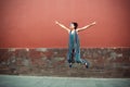 Young attractive woman jumping outdoor over red wall, image toned. Chinese girl amuses, summertime. Beautiful asian model has fun Royalty Free Stock Photo