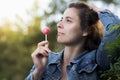 Young attractive woman licks caramel candy on an icicle on a stick in a park. A girl with a Chupa Chups in the open air. Royalty Free Stock Photo