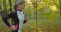 Young attractive woman listening music in the earphone while running in the city park. Royalty Free Stock Photo