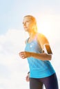 Young attractive woman listening to music with headphones on while running in park Royalty Free Stock Photo