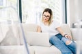 Young woman model sitting on a sofa using a laptop Royalty Free Stock Photo