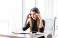 Young attractive woman at modern office desk, working on laptop, massaging temples to forget about constant headaches Royalty Free Stock Photo