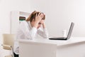 Young attractive woman at modern office desk, working on laptop, massaging temples to forget about constant headaches Royalty Free Stock Photo