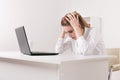 Young attractive woman at modern office desk, working on laptop, massaging temples to forget about constant headaches Royalty Free Stock Photo