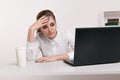 Young attractive woman at modern office desk, working on laptop, massaging temples to forget about constant headaches Royalty Free Stock Photo