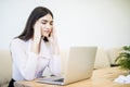 Young attractive woman at modern office desk, working on laptop, massaging temples to forget about constant headaches, noisy loud Royalty Free Stock Photo