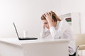 Young attractive woman at modern office desk, working on laptop, massaging temples to forget about constant headaches Royalty Free Stock Photo