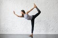 Young attractive woman in Natarajasana pose, studio background