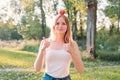 Young attractive woman outdoor holding red apple on her head, giving thumbs up and looking to camera with smile Royalty Free Stock Photo