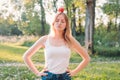 Young attractive woman outdoor holding red apple on her head and thinking about something on the blur nature background Royalty Free Stock Photo