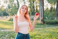 Young attractive woman outdoor holding red apple and thinking about something on the blur nature background. Lunch in Royalty Free Stock Photo