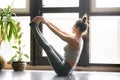 Young attractive woman in Paripurna Navasana pose, home interior