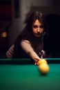 Young attractive woman playing billiard in club.