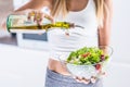 Woman pouring olive oil in to the vegetable salad.
