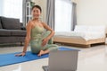 Young happy woman practicing yoga, sitting in Ardha Matsyendrasana exercise or Half lord of the fishes pose on mat in bedroom. Royalty Free Stock Photo