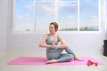 Young attractive woman practicing yoga, doing Half lord of the fishes exercise with namaste Royalty Free Stock Photo