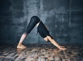 Young attractive woman practicing yoga standing in downward facing dog asana adho mukha svanasana pose