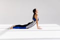 Young attractive woman practicing yoga, stretching in Cobra exercise, Bhujangasana pose, working out wearing sportswear, indoor Royalty Free Stock Photo