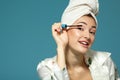 Young attractive woman putting eye mascara over blue, beauty tre Royalty Free Stock Photo