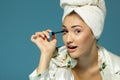 Young attractive woman putting eye mascara over blue background Royalty Free Stock Photo