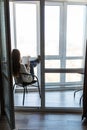 Young attractive woman read book and drink coffee sitting on balcony in apartment Royalty Free Stock Photo