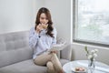 Young attractive woman read book and drink coffee sitting near window at home Royalty Free Stock Photo