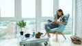 Young attractive woman read book and drink coffee sitting on balcony in modern loft apartment Royalty Free Stock Photo