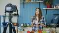 Young attractive woman recording video food blog about cooking on dslr camera in kitchen Royalty Free Stock Photo