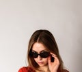 Young attractive woman in red on gray background with copy space. Woman posing with sunglasses. Scar on face Royalty Free Stock Photo