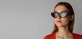 Young attractive woman in red on gray background. Woman posing with sunglasses. Scar on face Royalty Free Stock Photo