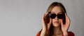 Young attractive woman in red on gray background. Woman posing with sunglasses. Scar on face Royalty Free Stock Photo
