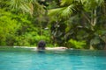 Young attractive woman relaxing happy at tropical beach luxury resort swimming at jungle infinity pool enjoying Summer holidays in Royalty Free Stock Photo