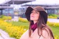Young attractive woman in sandy coat and brown hat on, a breath of fresh air in a city Park on the waterfront Royalty Free Stock Photo