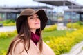 Young attractive woman in sandy coat and brown hat on, a breath of fresh air in a city Park on the waterfront Royalty Free Stock Photo