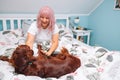 Young woman and her Irish Setter dog on bed at home. Portrait of a blonde young woman in pale pink pajamas with a dog Royalty Free Stock Photo