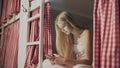 Young attractive woman sitting on the bed in the hostel room and using smartphone Royalty Free Stock Photo