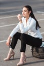 Young attractive woman sitting on car tire with lug wrench in her hand Royalty Free Stock Photo