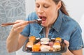 A Young attractive woman sitting on the sofa and eating sushi at home Royalty Free Stock Photo