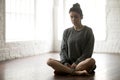 Young attractive woman sitting in Sukhasana pose, loft studio ba