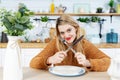 Young attractive woman sitting at table in kitchen with empty plate Royalty Free Stock Photo