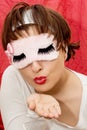 Young attractive woman in sleep mask sending kiss