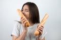 Young attractive woman smelling half of baguette in her hand standing on isolated white background dietology and nutrition