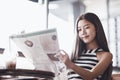 Young attractive woman smiling with happiness and enjoy reading a newspaper in the natural morning sunlight, mass media concept, Royalty Free Stock Photo