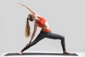 Young attractive woman standing in Reverse Warrior pose, grey st Royalty Free Stock Photo